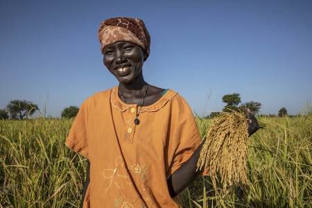 Woman smiling, rice plants South Sudan